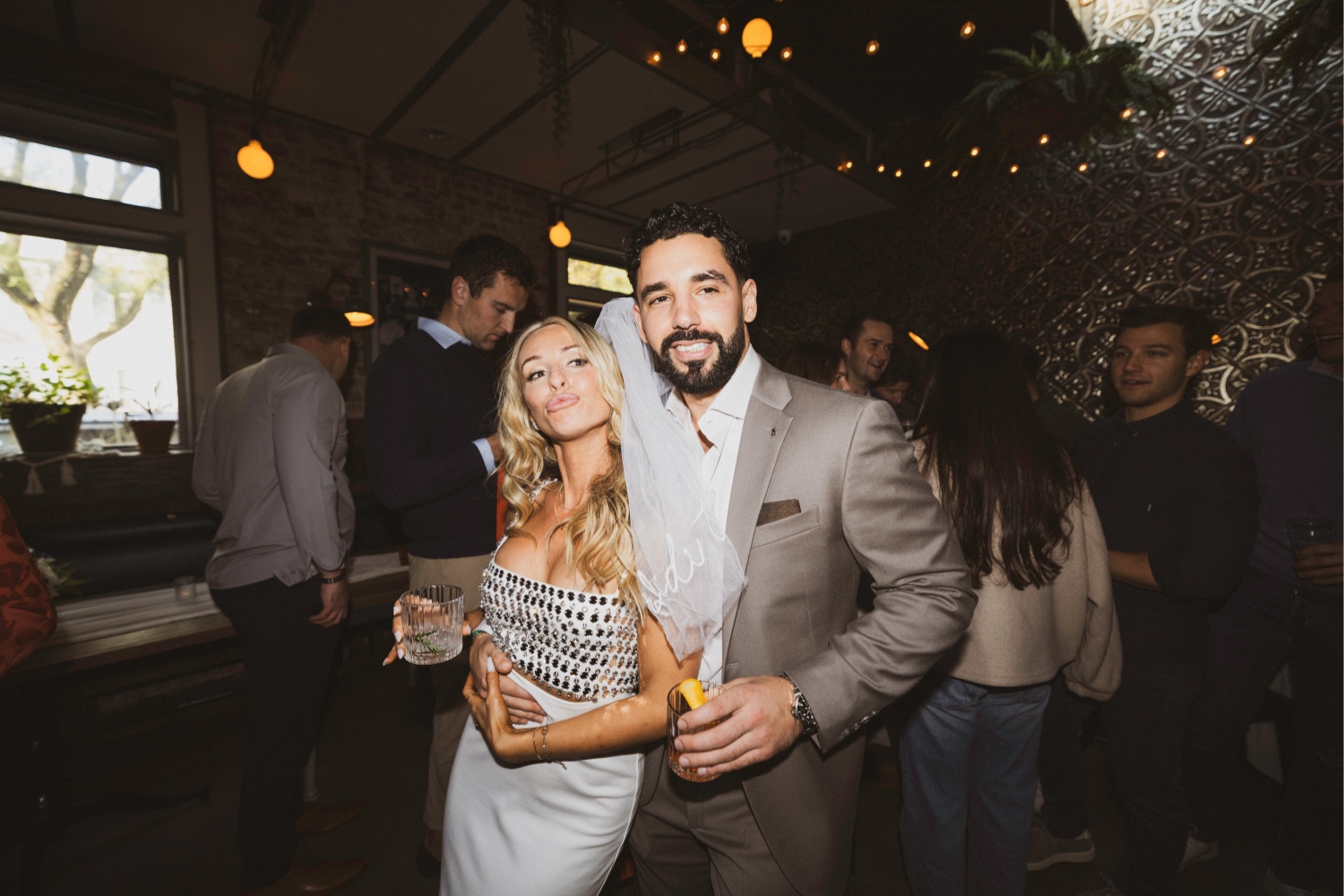 A bride and groom holding a drink taking a photo at their engagement party